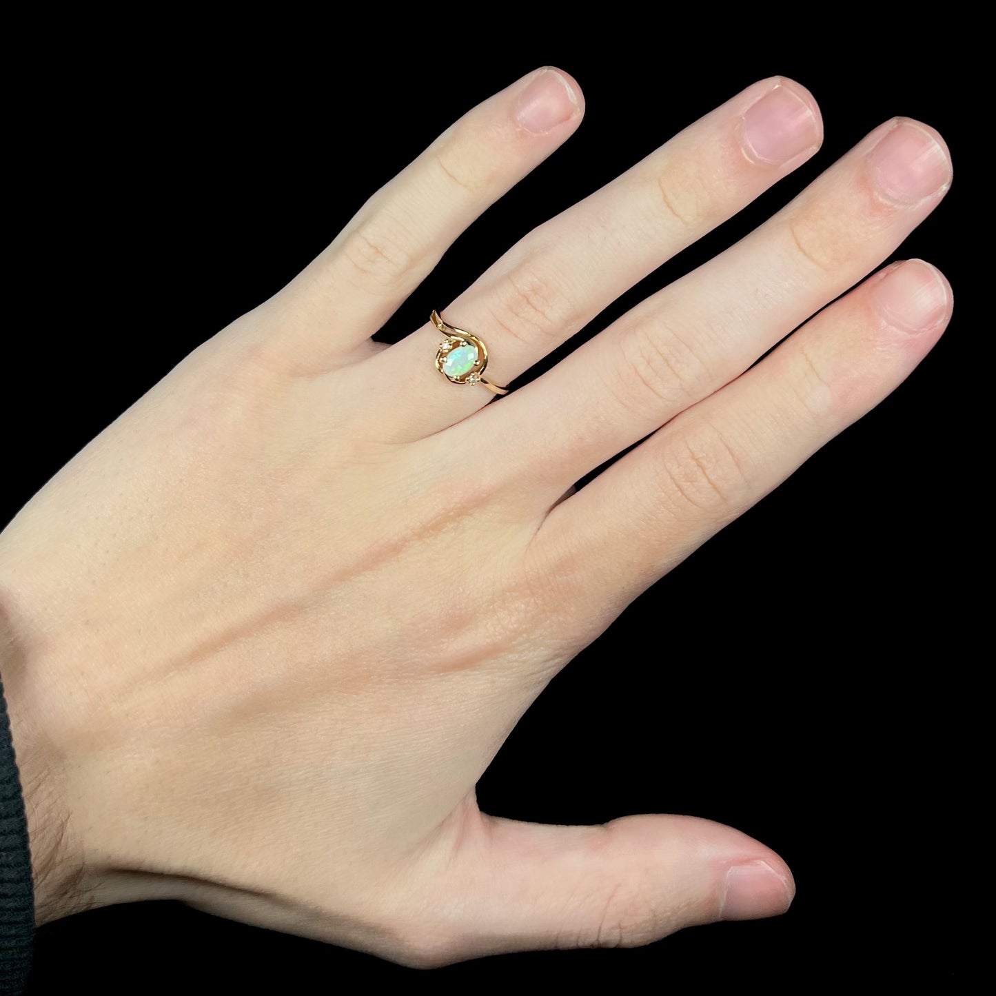 Hand wearing a vintage 1990s women's gold Australian opal and diamond ring.