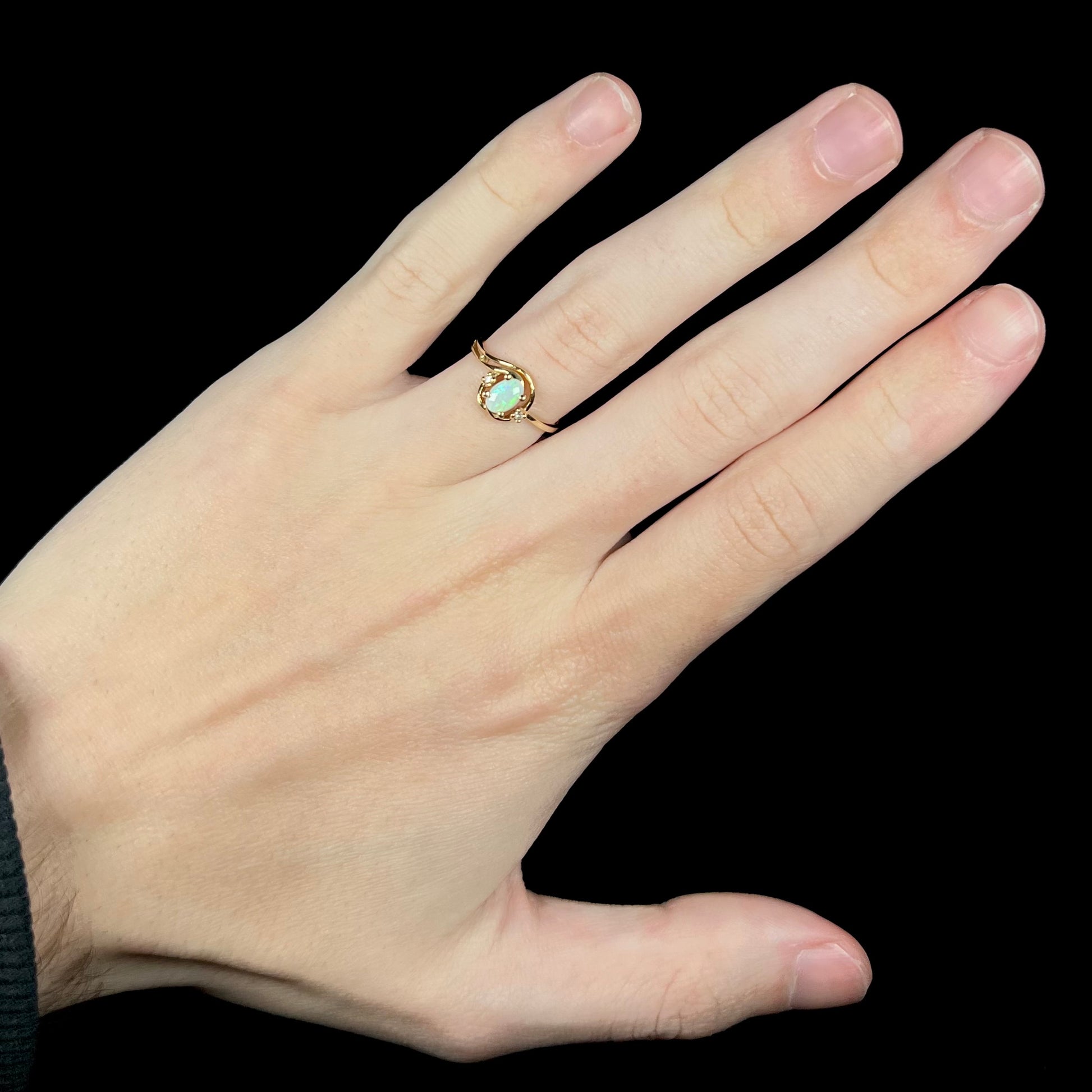 Hand wearing a vintage 1990s women's gold Australian opal and diamond ring.