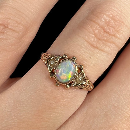 Close-up of women's antique White Cliffs, Australian opal and seed pearl ring, worn on finger