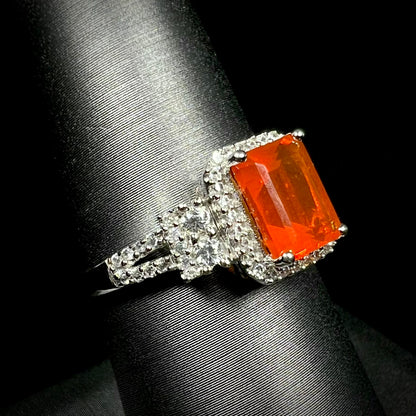 Women's white gold fire opal and zircon-accented ring shown from an angled macro view on a ring display against a black background.