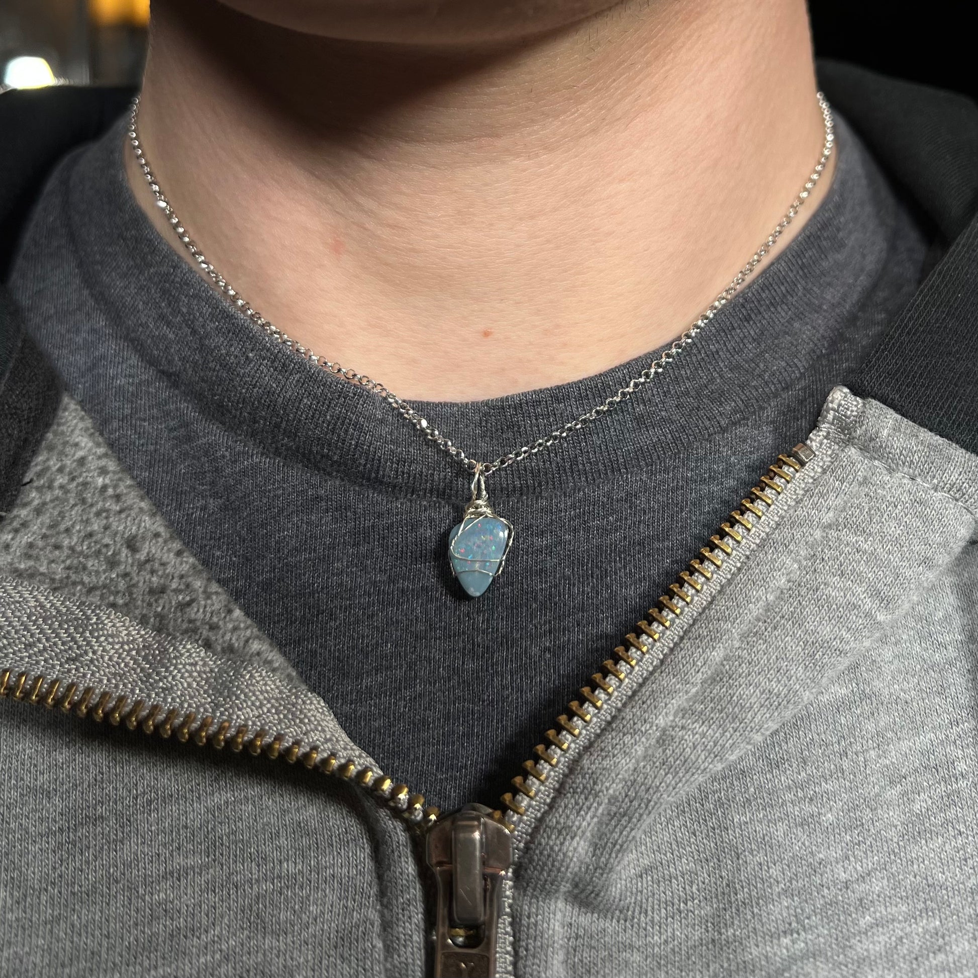 Close-up of person's neck wearing a women's 16" wire wrapped opal doublet necklace against a dark shirt beneath a hoodie.
