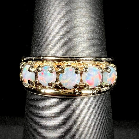 A yellow gold band set with five round cabochon cut opals and heart design accents.