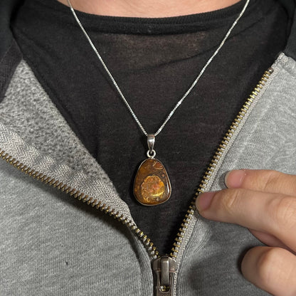 A Yowah nut boulder opal necklace in sterling silver, shown worn around a neck against a dark shirt.