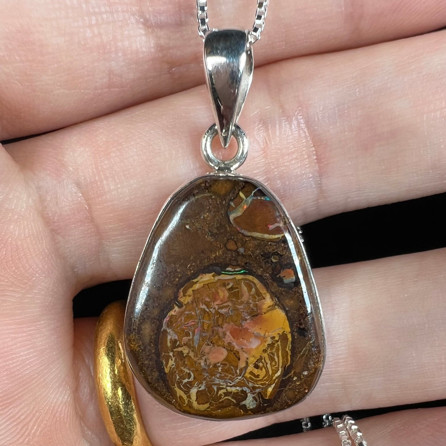 Close-up of a Yowah nut boulder opal pendant in sterling silver, shown under LED light.