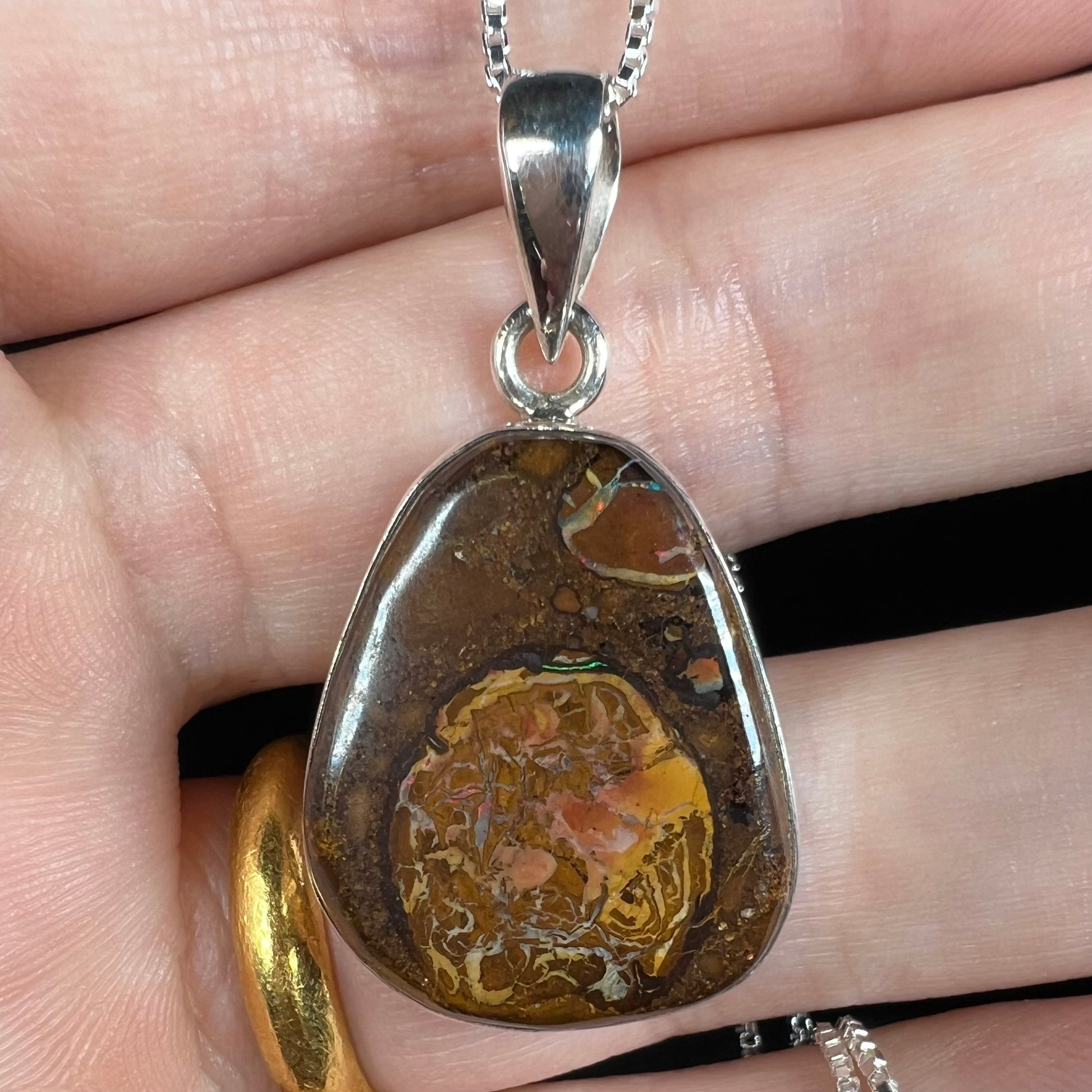 Close-up of a Yowah nut boulder opal pendant in sterling silver, shown under LED light.